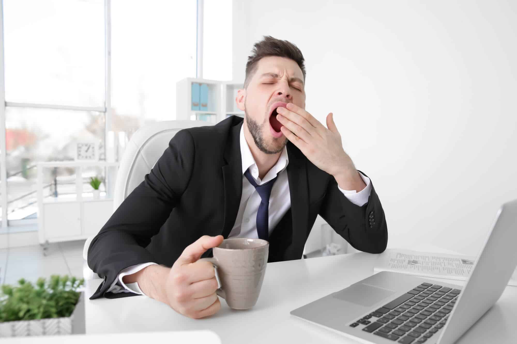 Мужчина постоянно уставший. Зевающий человек. Усталый офисный работник. Парень зевает. Скука на работе.